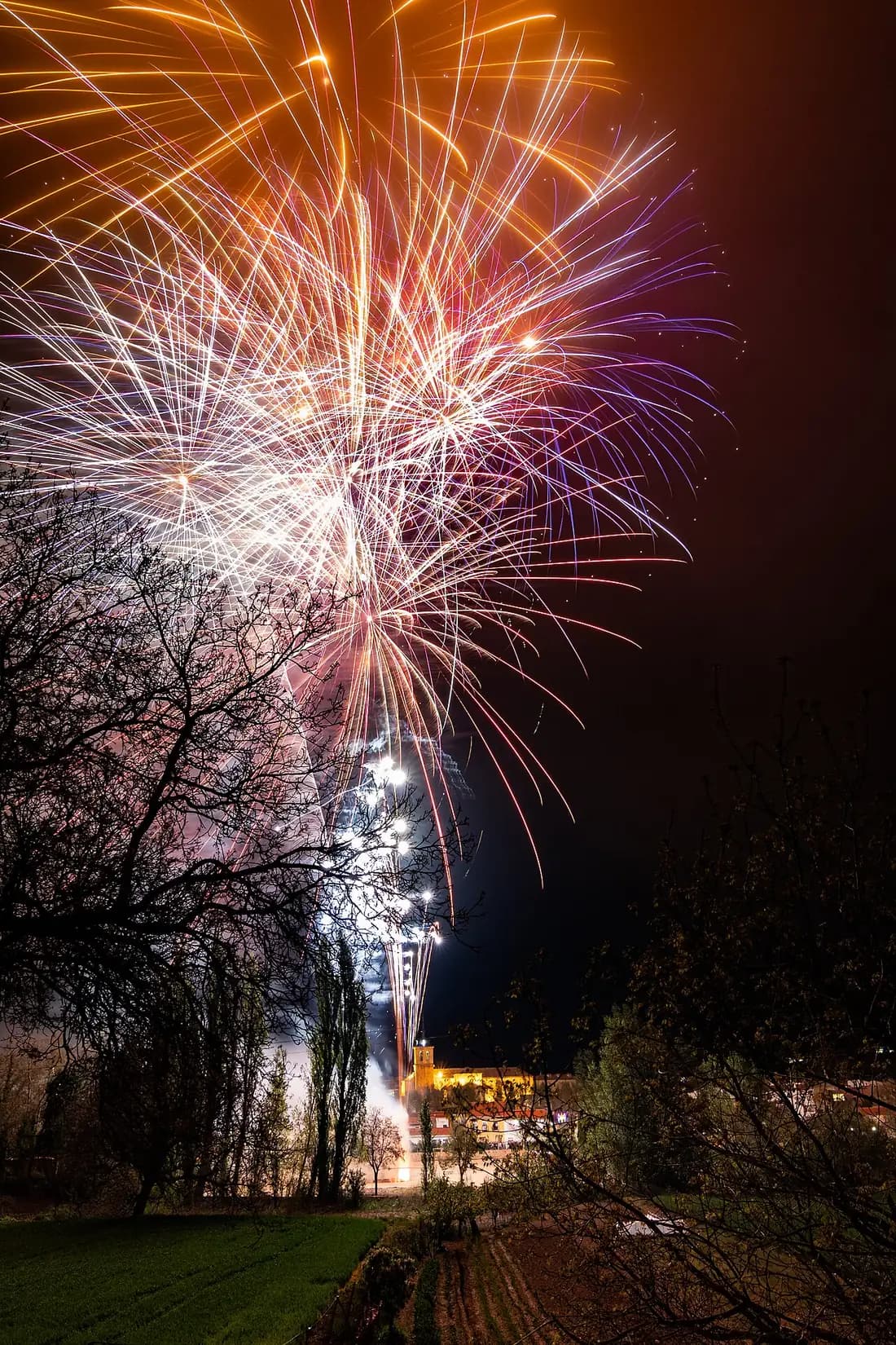 Fuegos artificiales sobre las casas y el campanario de Lezuza durante sus fiestas de mayo
